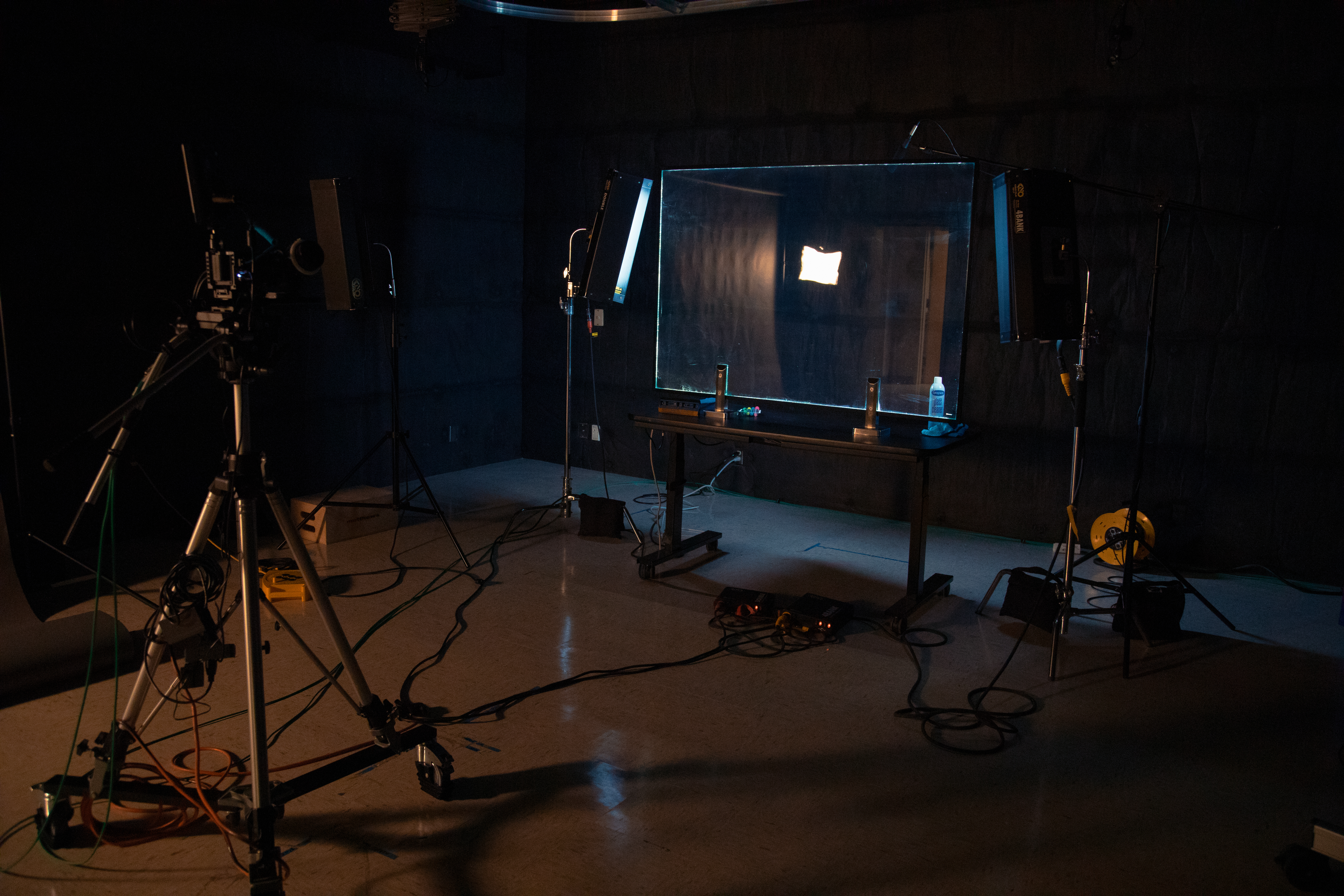 a darkened studio with a camera pointed at a transparent board atop a table