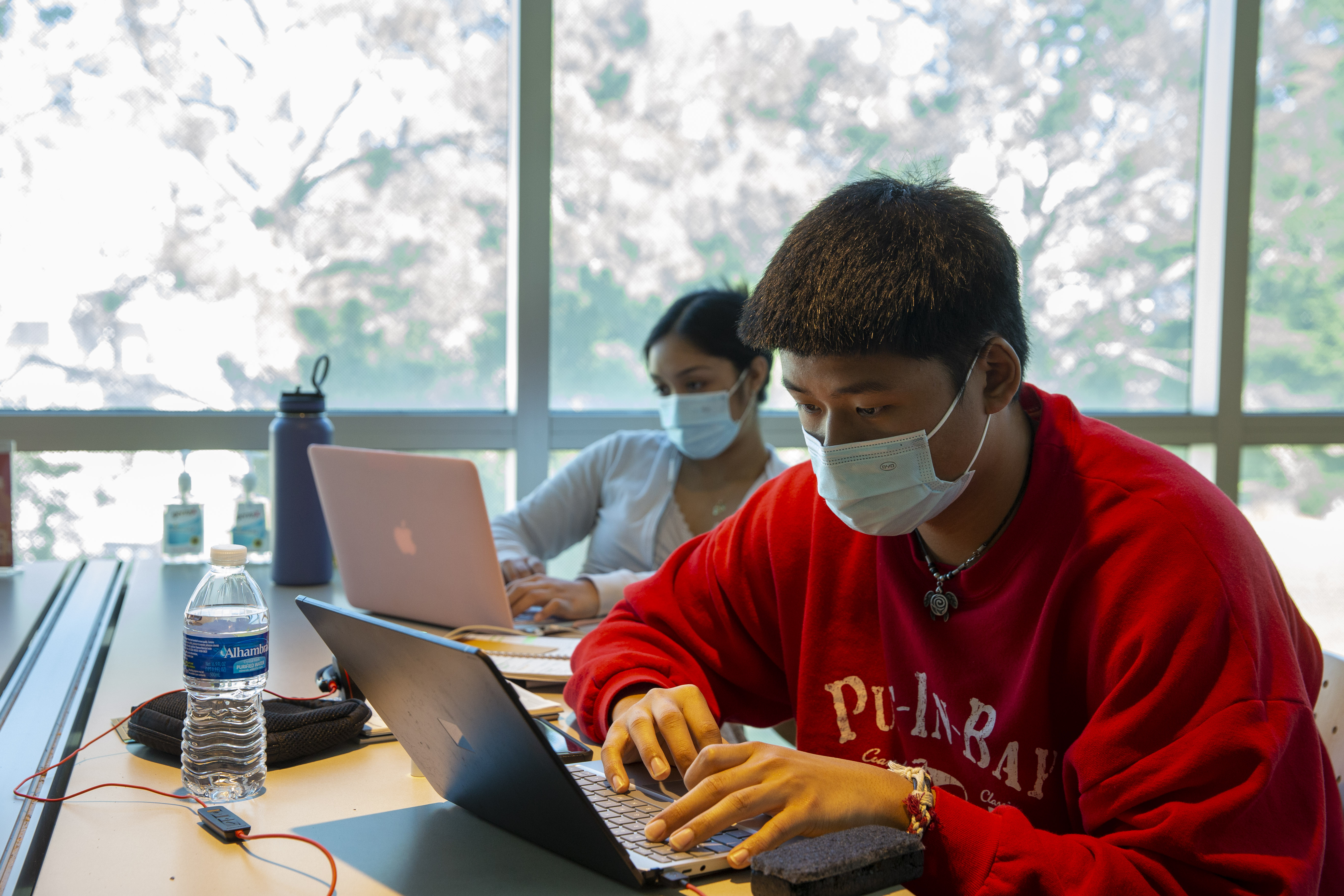 two students on laptops with masks on