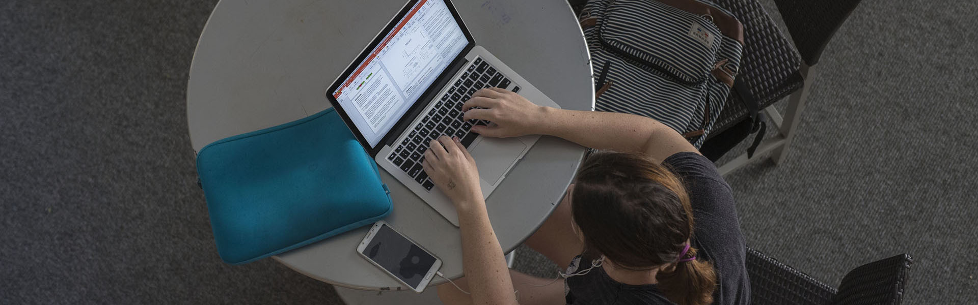 Overhead angle photo of a student on a laptop computer at a round table.